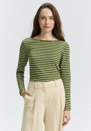 Haut à manches longues rayé vert et blanc avec un décolleté bateau, associé à un pantalon beige ajusté. Tissu lisse, design près du corps.