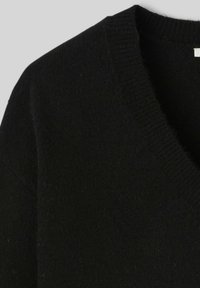 Pull en laine noir avec un design en V et un col côtelé. Le tissu semble doux et texturé avec une surface légèrement duveteuse.