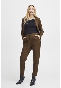 Bruine pinstriped colbert en bijpassende broek met een trekkoord in de taille. Zwarte getailleerde top en zwarte enkellaarsjes. Glad weefsel, taillerende pasvorm.