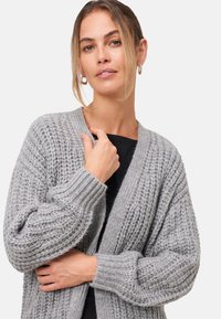 Grijze gebreide cardigan met een gestructureerd patroon, open voorkant en geribde mouwen. Zacht, chunky materiaal, geschikt voor casual kleding.