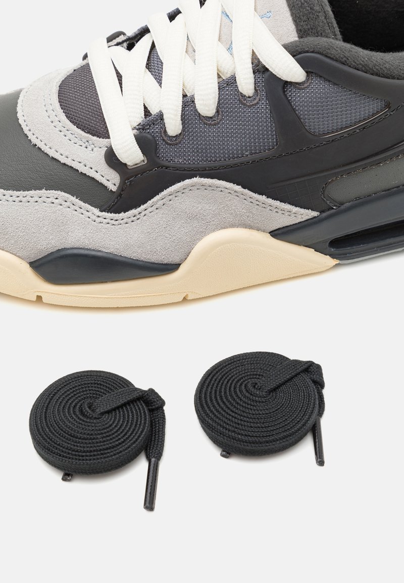 Chaussure de sport avec tige en suède gris, supérieur en synthétique noir, accents en maille et semelle en caoutchouc crème. Comprend deux lacets ronds noirs.