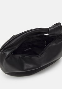 Pochette en cuir noir doux avec une poignée nouée et une ouverture zippée montrant une poche intérieure zippée et une étiquette de marque even&odd.
