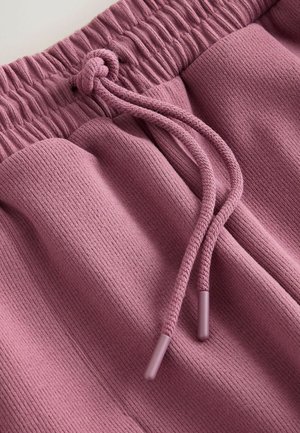 Lila Sweatpants mit Kordelzug und geripptem Stoff, ausgestattet mit elastischem Bund und zwei seitlichen Taschen; die Enden des Kordelzugs sind in der gleichen Farbe ausgeführt.