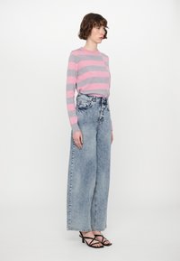 Striped sweater in pink and gray, paired with high-waisted, wide-leg light wash denim jeans. Strappy black sandals complete the outfit.