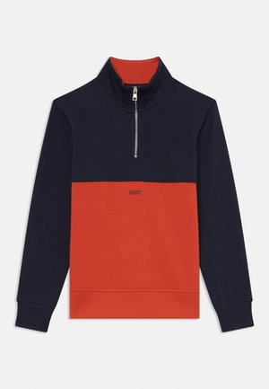 Half-zip sweatshirt med en marineblå topp og lys rød nedre del. Laget av myk stoff med ribbestrikkede mansjetter og krage, pyntet med logo.