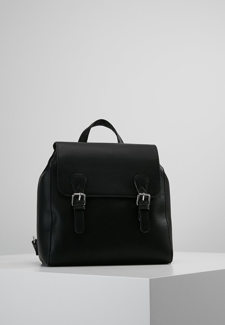Mochila de cuero negro con cierre de solapa, dos hebillas metálicas, un asa superior y correas de hombro ajustables. Textura suave sin patrones.