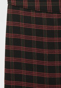 Tessuto nero con un motivo a quadri rosso e verde. Presenta una trama finemente tessuta e dettagli di cucitura a contrasto lungo le cuciture.