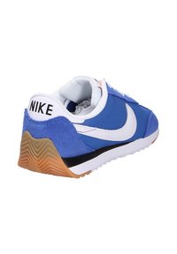 Baskets bleues avec tige en suède et textile, accents et logo blancs, col rembourré, semelle extérieure en caoutchouc avec un motif texturé, et détails noirs.