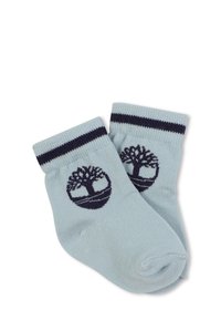 Calzini azzurri con polsini a righe navy e un logo circolare a forma di albero su ciascun lato. Realizzati in un materiale morbido e traspirante.