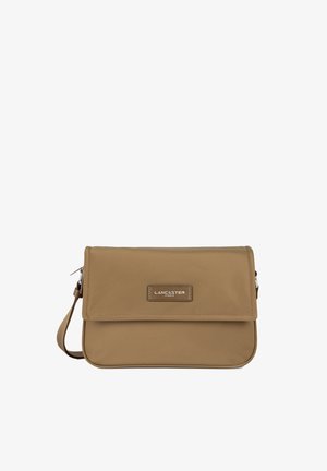 Sac en matériau synthétique tan avec une fermeture à rabat, présentant une plaque de logo de marque en métal et une sangle ajustable.