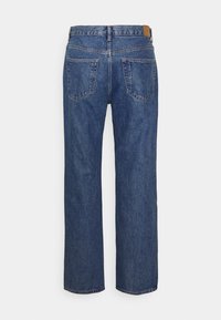 Bredde jeans i mellemblå denim med høj talje, baglommer og en brun læderlap i taljebåndet.