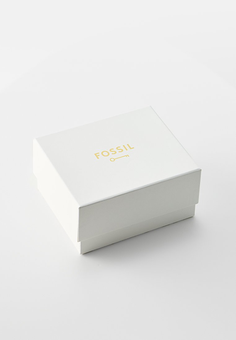 Boîte rectangulaire blanche avec une finition brillante, arborant un logo doré "FOSSIL" sur le dessus, conçue pour emballer des accessoires.
