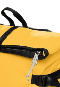 Mochila amarilla con una superficie texturizada, cremalleras negras y un tirador plateado. Cuenta con correas negras y un bolsillo exterior con cremallera.