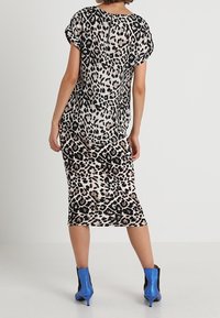 Midi šaty s leopardím potiskem, krátkými rukávy, splývavou tkaninou a decentním zadním zipem. Nosit s modrými vysokými kotníkovými botami.