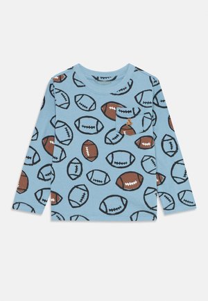 Lichtblauw blouse met lange mouwen, voorzien van een patroon van bruine en zwarte voetballetjes, met een kleine zak versierd met een bruine voetbal.