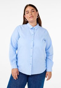 Camicia a maniche lunghe blu chiaro con colletto alla francese, patta anteriore e bottoni abbinati. Realizzata in tessuto liscio, presenta un orlo curvo.