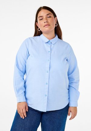 Light blue long-sleeve shirt with a button-down collar, front placket, and matching buttons. Made of smooth textile, features a curved hem.