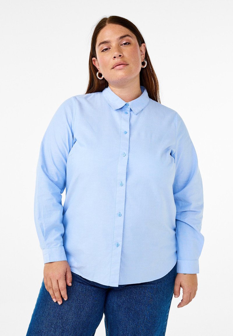 Camicia a maniche lunghe blu chiaro con colletto alla francese, patta anteriore e bottoni abbinati. Realizzata in tessuto liscio, presenta un orlo curvo.