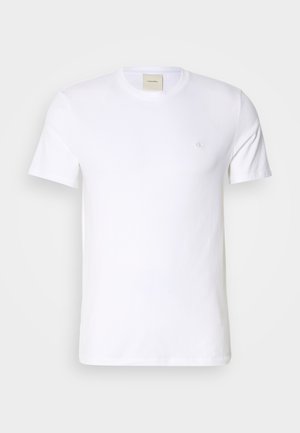T-shirt en coton blanc avec un col rond, des manches courtes et un petit logo brodé sur la poitrine gauche. Texture lisse.