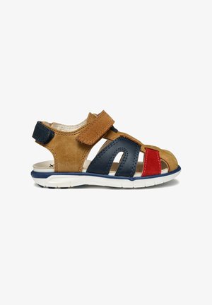 Sandalias de cuero marrón y azul marino con acentos rojos y marrones, diseño abierto, correa de velcro, superficie texturada y suela de goma blanca.