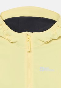 Helle gelbe Jacke mit einem Reißverschluss vorne und einer weichen schwarzen Fleece-Innenseite. Verfügt über eine elastische Kapuze und ein Logo auf der linken Brustseite.