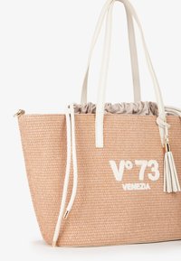 Borsa intrecciata beige con manici in pelle bianca, chiusura a coulisse e una nappina decorativa. Presenta il marchio in bianco "V°73 VENEZIA."