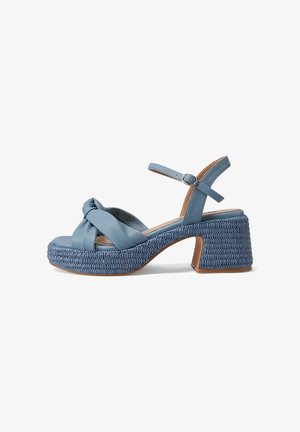 Sandalia de tacón azul de cuero con tira anudada, suela de plataforma tejida y correa ajustable en el tobillo con hebilla.