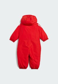 Un traje de nieve rojo para bebé con capucha adjunta y puños elásticos en las mangas y piernas, mostrado desde la parte trasera sobre un fondo liso.