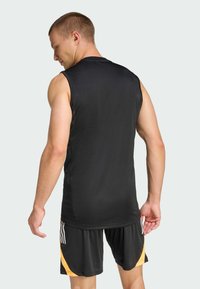 Svart ärmlös träningstop i fukttransporterande tyg, matchad med svarta shorts med gula accenter och tre vertikala ränder.