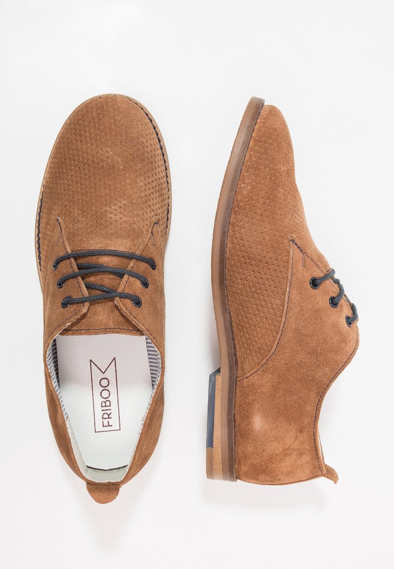 Hnědé semišové boty s perforovaným designem, kulatou špičkou, černými šněrováním a malým podpatkem. Interiér má pruhované podšívku.