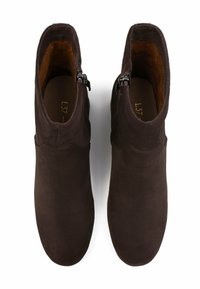 Bottines en suede marron avec une texture lisse, un bout arrondi et des fermetures éclair sur les côtés. L'intérieur présente une doublure contrastante en beige.