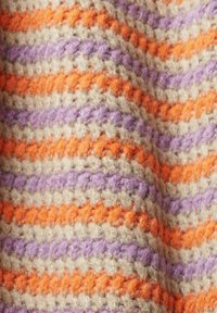 Vävd filt med växlande ränder av orange, lila och beige garn som har en texturerad, mysig utseende.