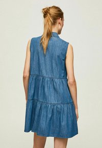 Denim ilmanhihaisuus mekko, jossa on kerrostettu muotoilu, vyötärö on kireä ja helma on levenevä. Sininen kangas, joka on sileä ja jossa on kaulus.