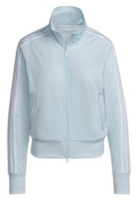 Chaqueta de chándal Adidas de color azul claro con rayas blancas en las mangas, cierre de cremallera en el frente, bolsillos laterales y cuello alto.