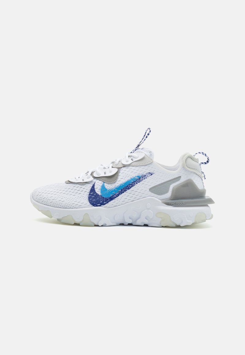 Baskets blanches avec tige en mesh, logo Nike bleu et irisé, accents gris et semelle blanche robuste. Présente un motif texturé et un laçage.