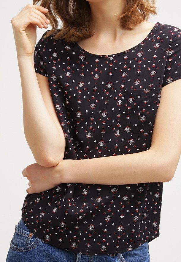 Haut noir à manches courtes avec un motif floral en rouge, blanc et bleu. Encolure ronde avec une petite poche sur la poitrine et une texture de tissu douce.