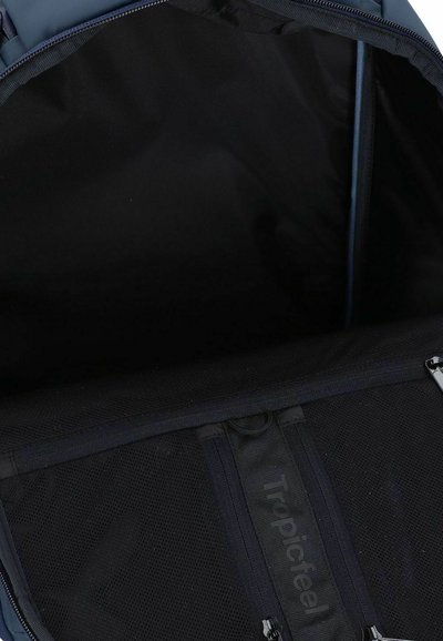 Interior de mochila de color azul oscuro con bolsillo de malla negra y compartimentos con cremallera. Textura suave sin patrones visibles ni detalles de hardware.