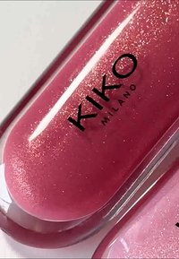 Brillo labial Kiko Milano en rosa brillante con sutil destello, envase transparente y logo en texto negro en negrita. Textura suave, forma redondeada.