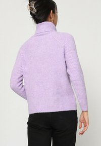 Pull-over col roulé en maille côtelée de couleur violet clair, à manches longues, doté d'une coupe décontractée et de fentes sur les côtés à l'ourlet. Vue arrière affichée.