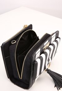 Borsa a strisce bianche e nere realizzata in materiale testurizzato, con molteplici scomparti, hardware dorato e un fusciacca decorativa.