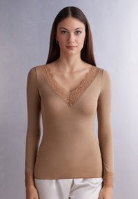 Top marrón ajustado de mangas largas con un escote en V profundo. El borde de encaje a lo largo del escote y los puños de las mangas añade textura y detalle. Tejido suave.