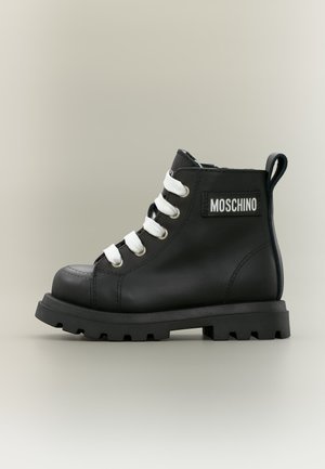 Μαύρο δερμάτινο μποτάκι Moschino με χοντρή σόλα και λευκά κορδόνια, με λαβή και λογότυπο στο πλάι.