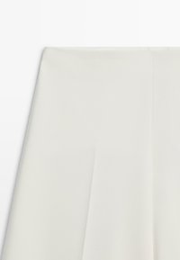 Biały, teksturowany materiał o gładkim wykończeniu, z plisami i czystym, prostym wzorem. Brak widocznych elementów metalowych ani ozdób.