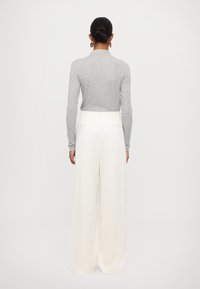 Gray long-sleeve turtleneck top paired with loose, cream-white wide-leg trousers, featuring subtle texture and minimalistic design.