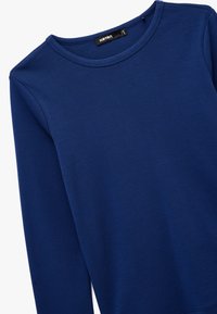 Marineblauwe sweatshirt met lange mouwen, gemaakt van een zachte katoenen mix. Voorzien van een klassieke ronde halslijn en geribde manchetten, zonder patronen of grafieken.