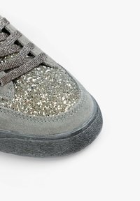 Gray suede sneaker with shiny glitter detailing on the upper, textured black rubber sole, and gray laces. Close-up view of the shoe's front.