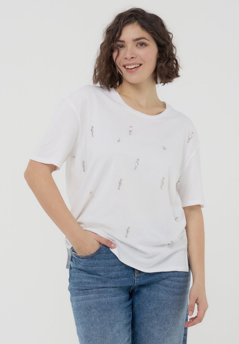 T-shirt bianco a maniche corte con decorazioni in argento sparse sul davanti, caratterizzato da una vestibilità comoda e un collo arrotondato.