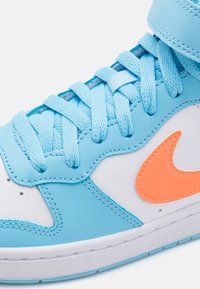 Sneaker alta con tomaia in pelle blu chiaro, pannelli laterali bianchi e logo swoosh arancione. Presenta lacci piatti e colletto imbottito.
