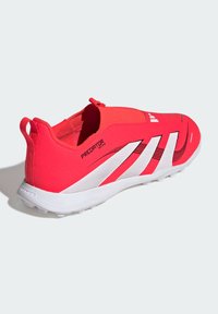 Zapatillas deportivas rojas con un diseño sin cordones, parte superior de tela texturizada, detalles en blanco y una suela de goma que presenta tracción moldeada.