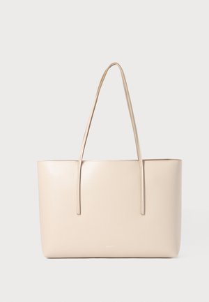 Geantă tote din piele bej, cu două curele lungi, formă rectangulară, textură netedă și design minimalist. Fără hardware vizibil sau modele.